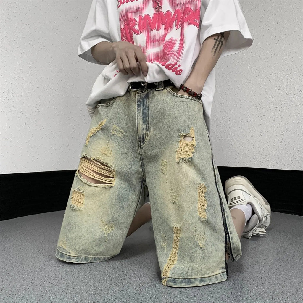 Men's loose five-point denim shorts in blue with ripped yellow-mud effect, straight leg, button fly, front view