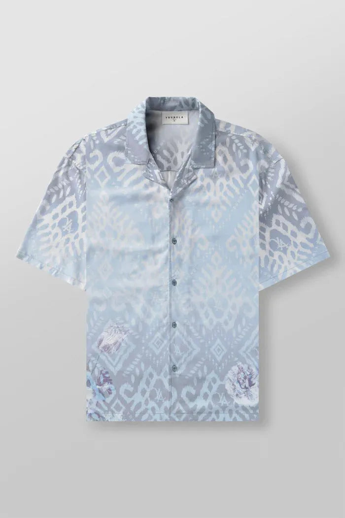 Man wearing a loose grey short-sleeve top with a floral print pattern