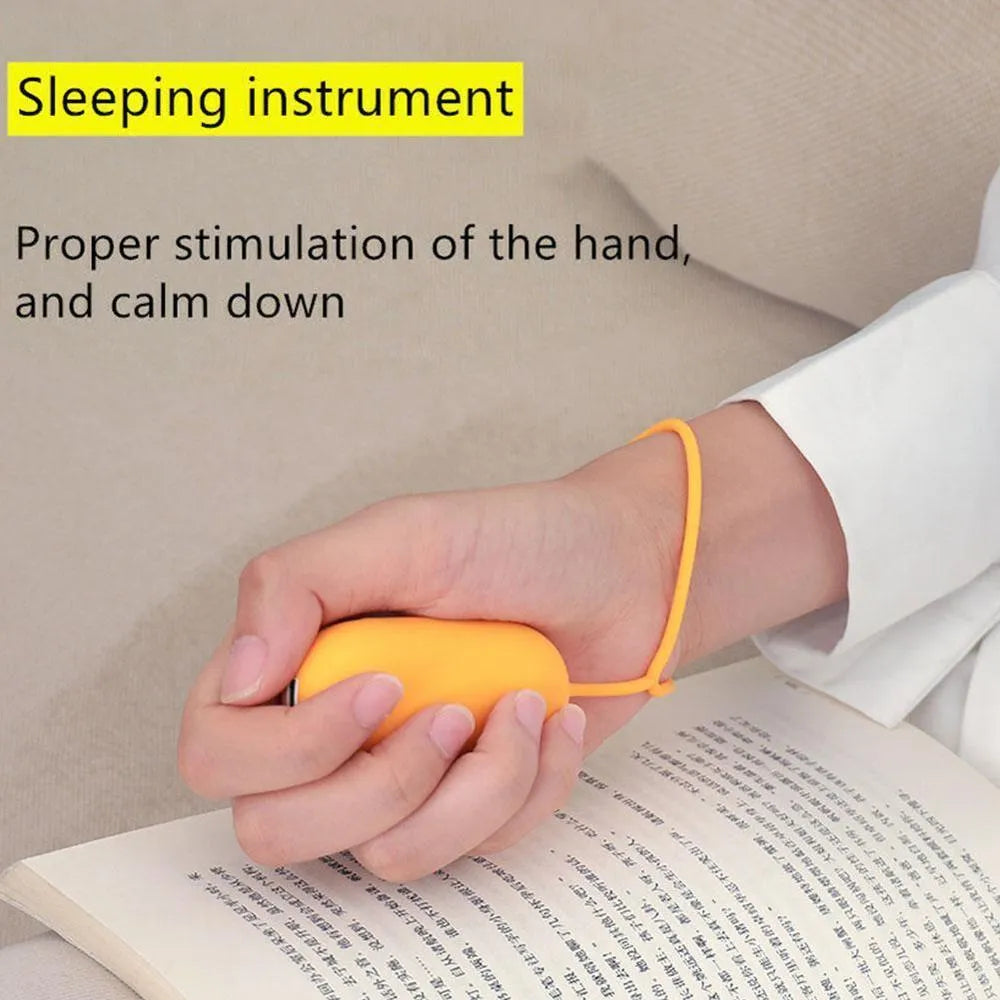 Hand-held micro-current sleep aid device in grey, with round button and micro USB port, on a desk