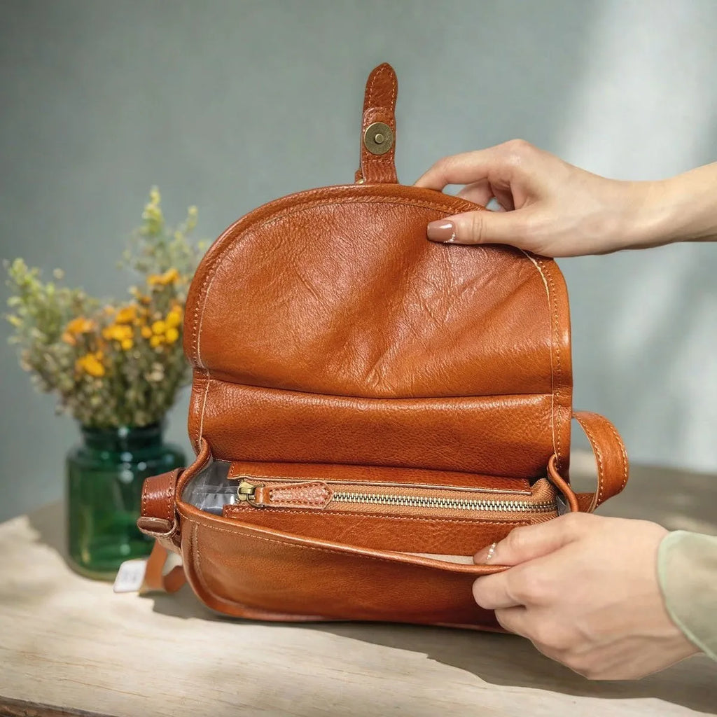 Genuine leather messenger bag in brown, soft shell shape with flap closure and visible sewing detail