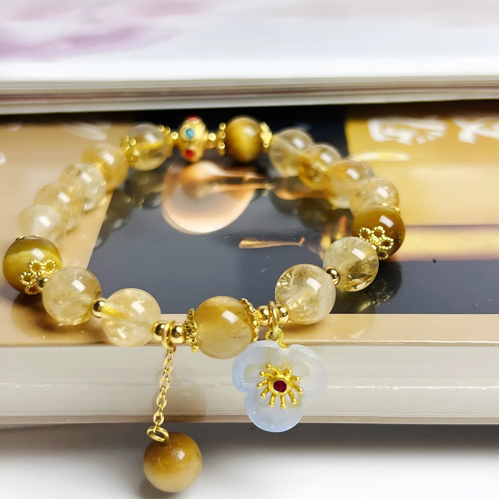 Women's handcrafted citrine crystal bracelet with flower tassel pendant on white background