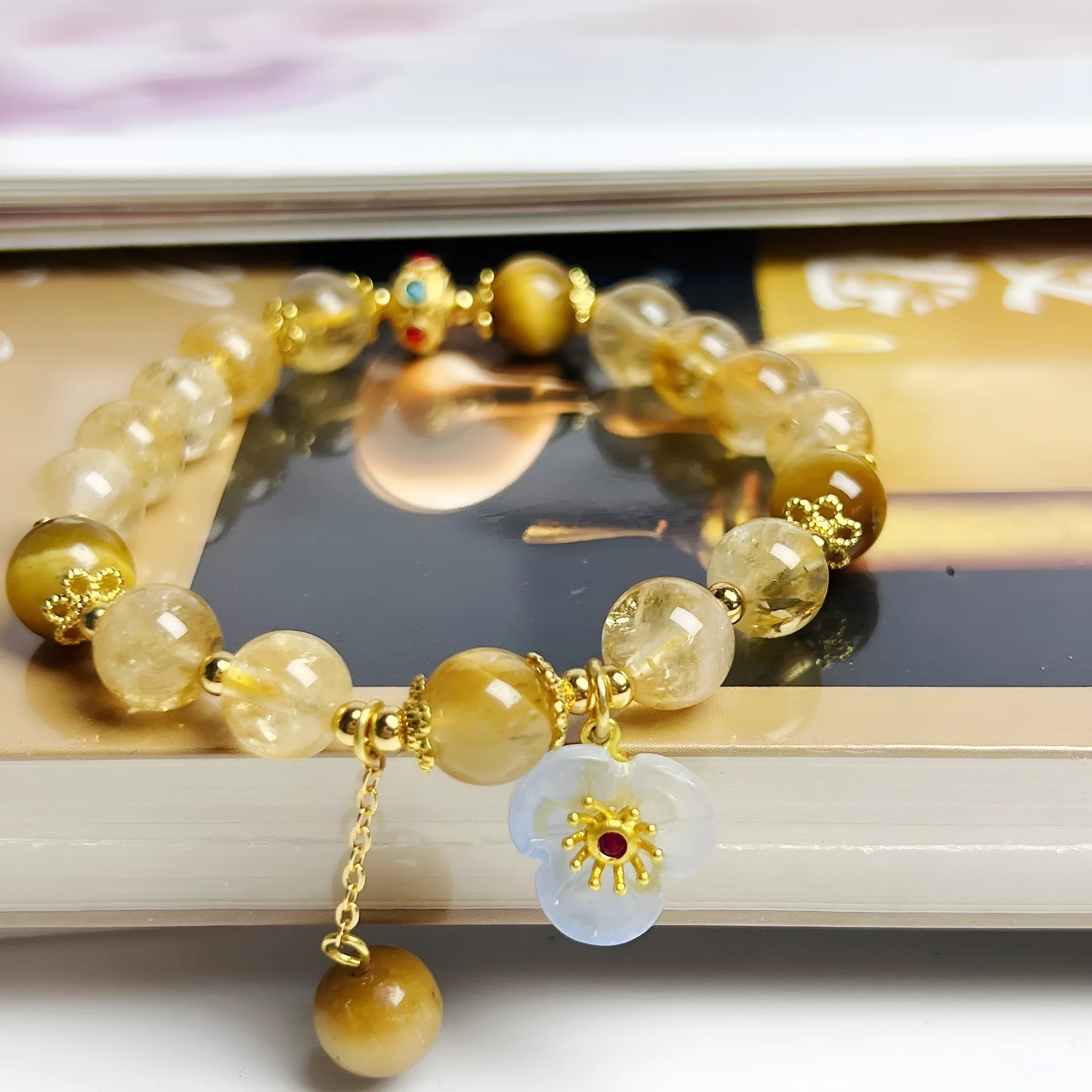 Women's handcrafted citrine crystal bracelet with flower tassel pendant on white background