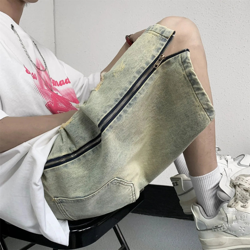 Men's loose five-point denim shorts in blue with ripped yellow-mud effect, straight leg, button fly, front view