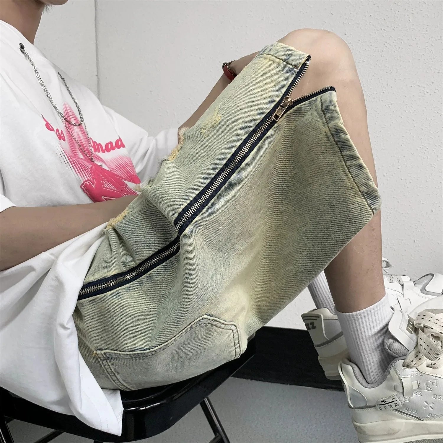 Men's loose five-point denim shorts in blue with ripped yellow-mud effect, straight leg, button fly, front view
