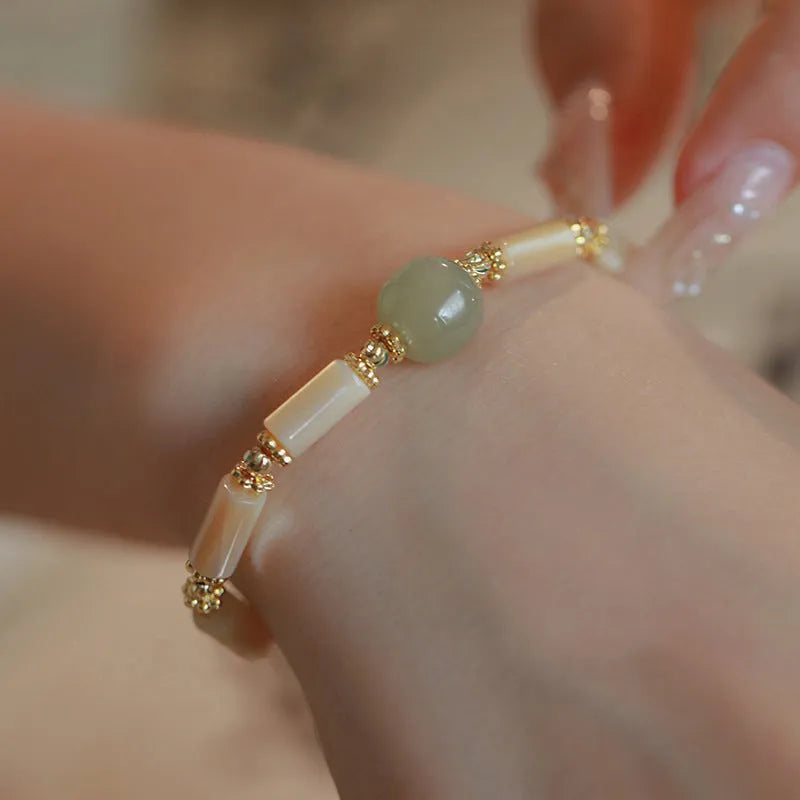 Natural Hetian jade white lip shell round bead bracelet for women on a neutral background