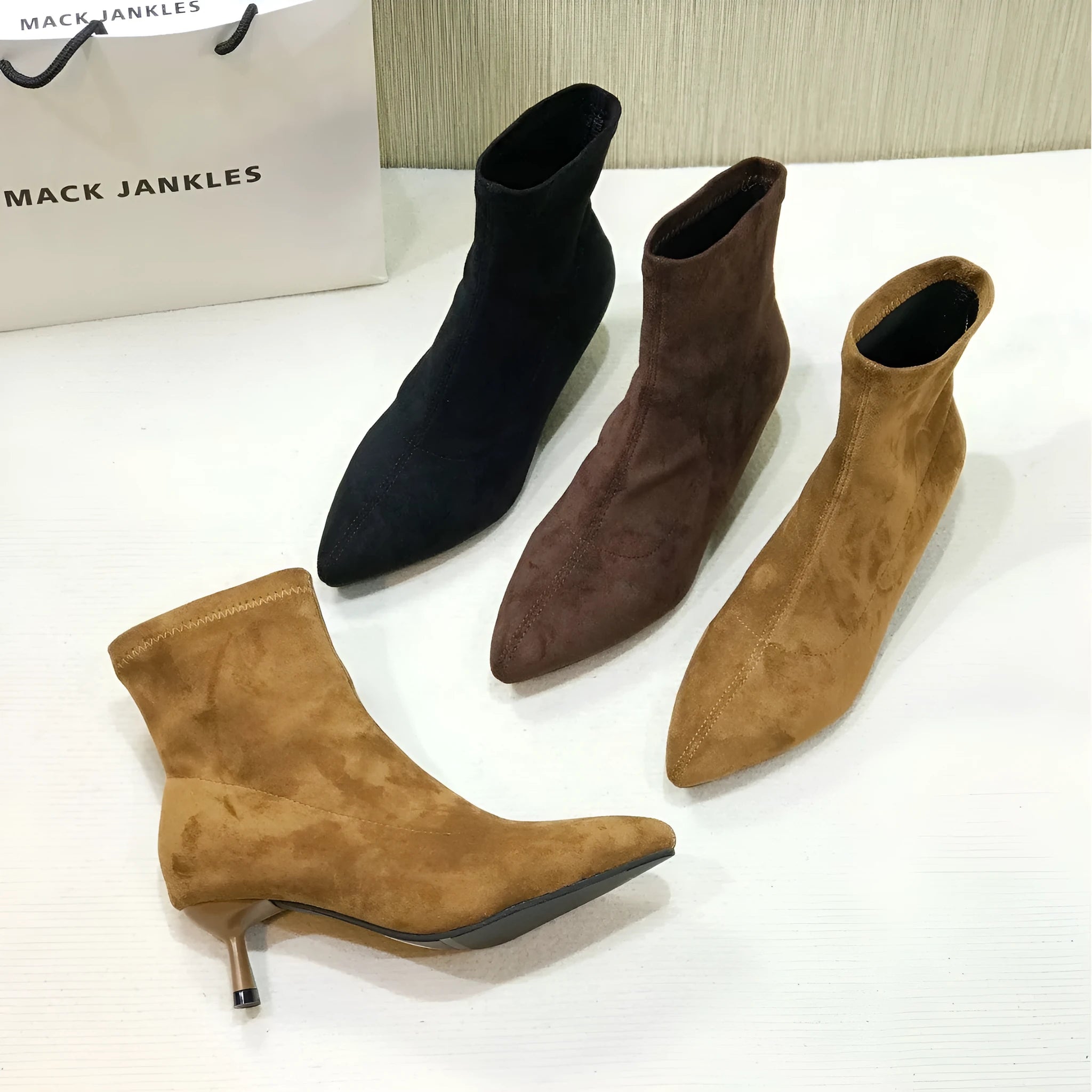 Women's black pointed toe ankle boots with a stiletto heel on a plain background