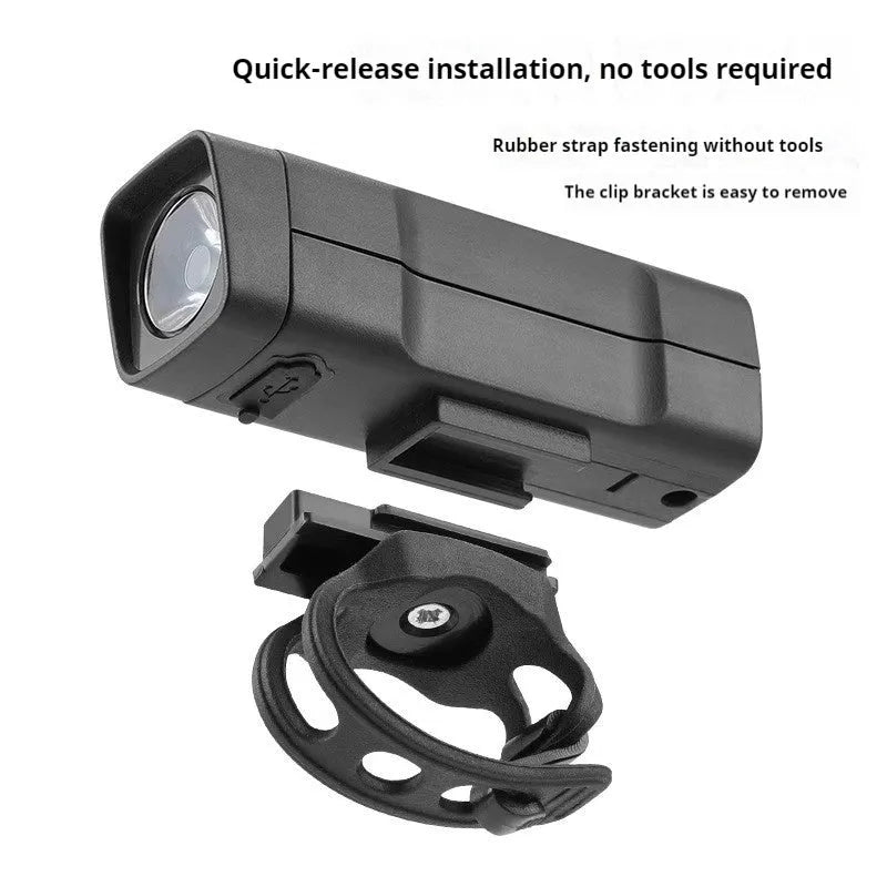 Black USB-rechargeable bicycle headlight mounted on bike handlebars with strap bracket.