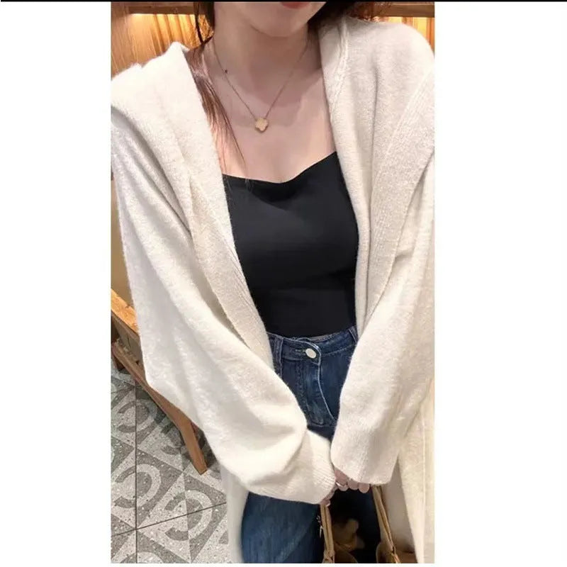 A woman wearing a long, loose, hooded beige knitted cardigan in a Korean casual style.
