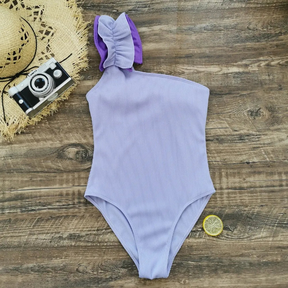 Women's single-shoulder one-piece swimsuit with a suspender strap in a solid colour.