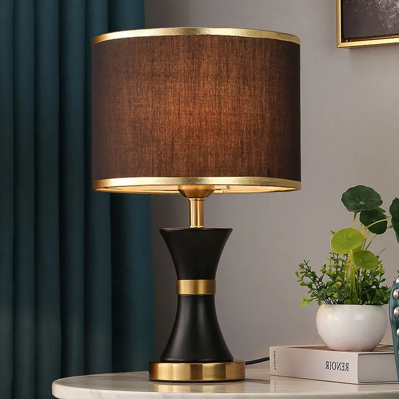 Simple bedroom table lamp with black iron body and cloth lampshade on a desk