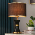 Simple bedroom table lamp with black iron body and cloth lampshade on a desk