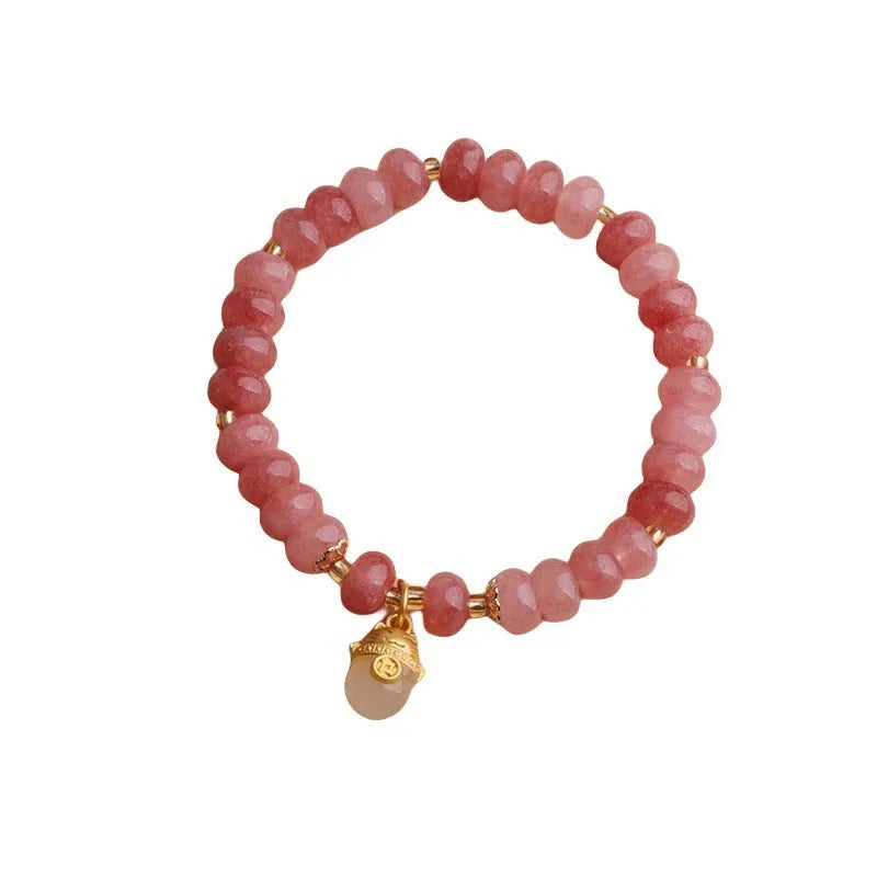 Women's handmade strawberry quartz Lucky Cat bracelet on a neutral background