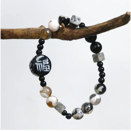 Natural black agate and ceramic round bead hand-woven bracelet on plain background, unisex original design