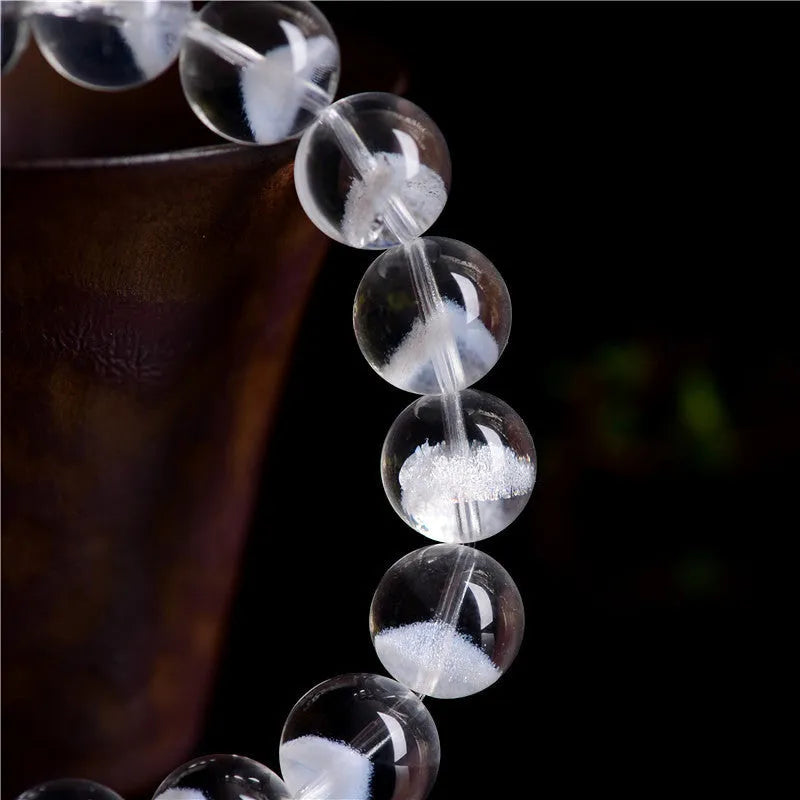 Close-up of a women's white crystal ghost pyramid bracelet with a Ruyi charm on a wrist.