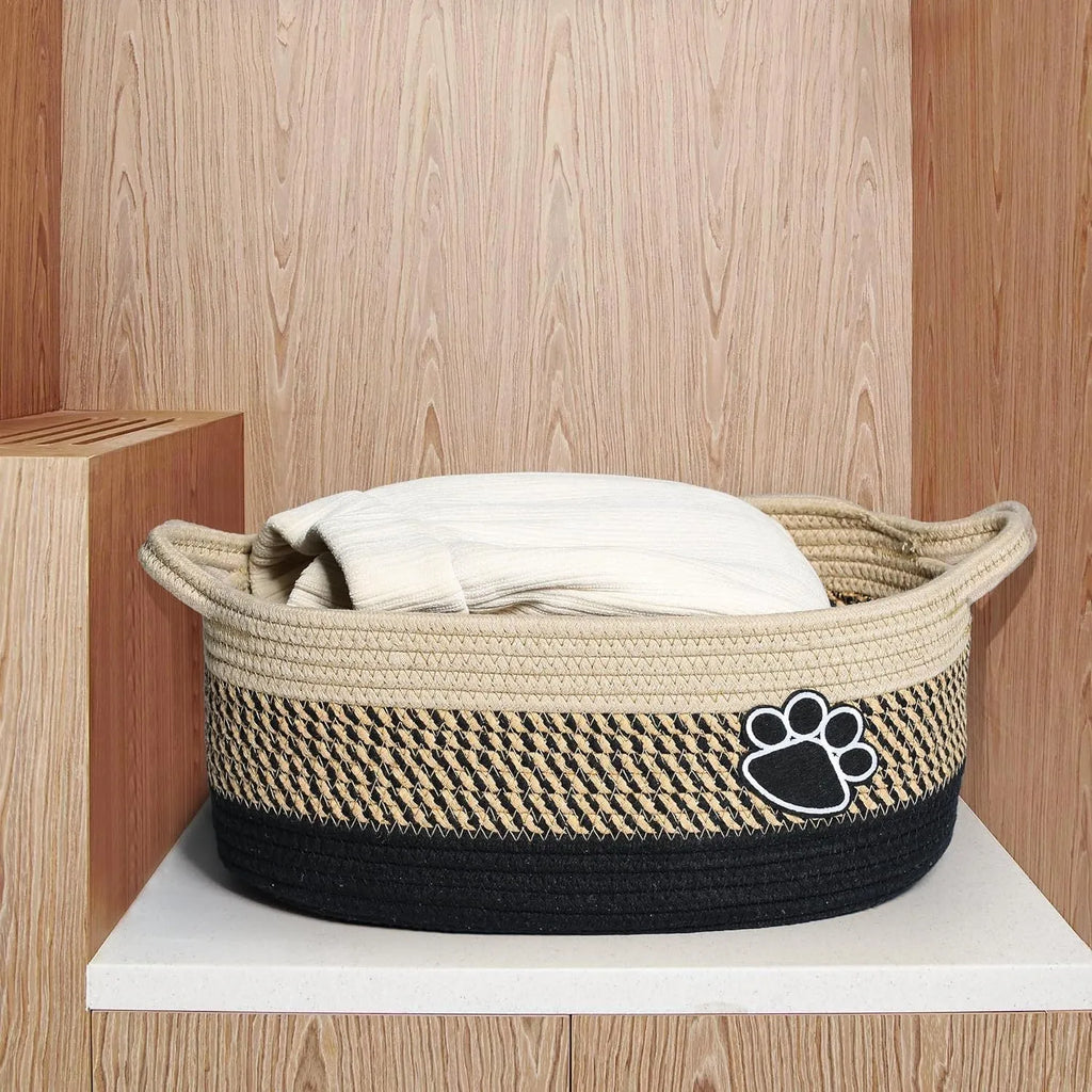 Small light beige woven cotton rope storage basket with handles on a wooden surface.