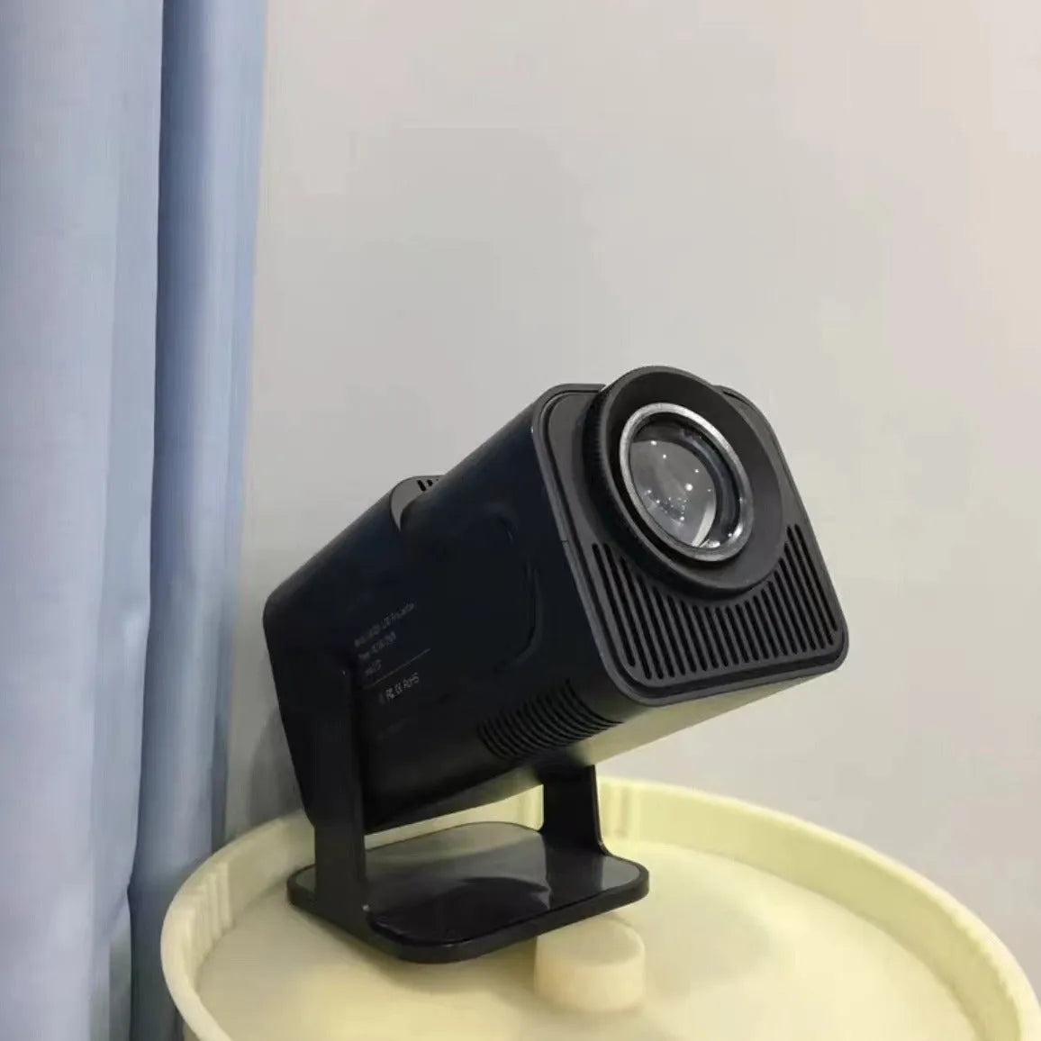 A wireless home projector with a carrying handle, displaying a bright game or movie on a wall.
