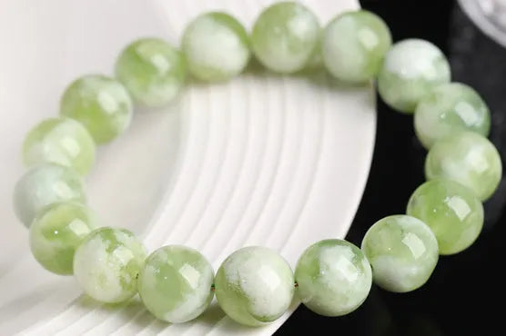 Green milk-in-water Xiuyan jade bracelet with polished geometric beads on white background