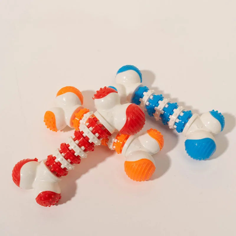 Blue, orange, and red bone-shaped rubber dog chew toy with a treat slot, shown next to dog biscuits.