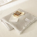 Four-layer gauze tassel cotton blanket in avocado green colour laid flat.