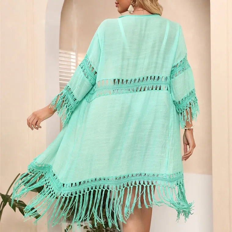 Women's yellow hand-crocheted acrylic beach cardigan with tassel detailing on a hanger.