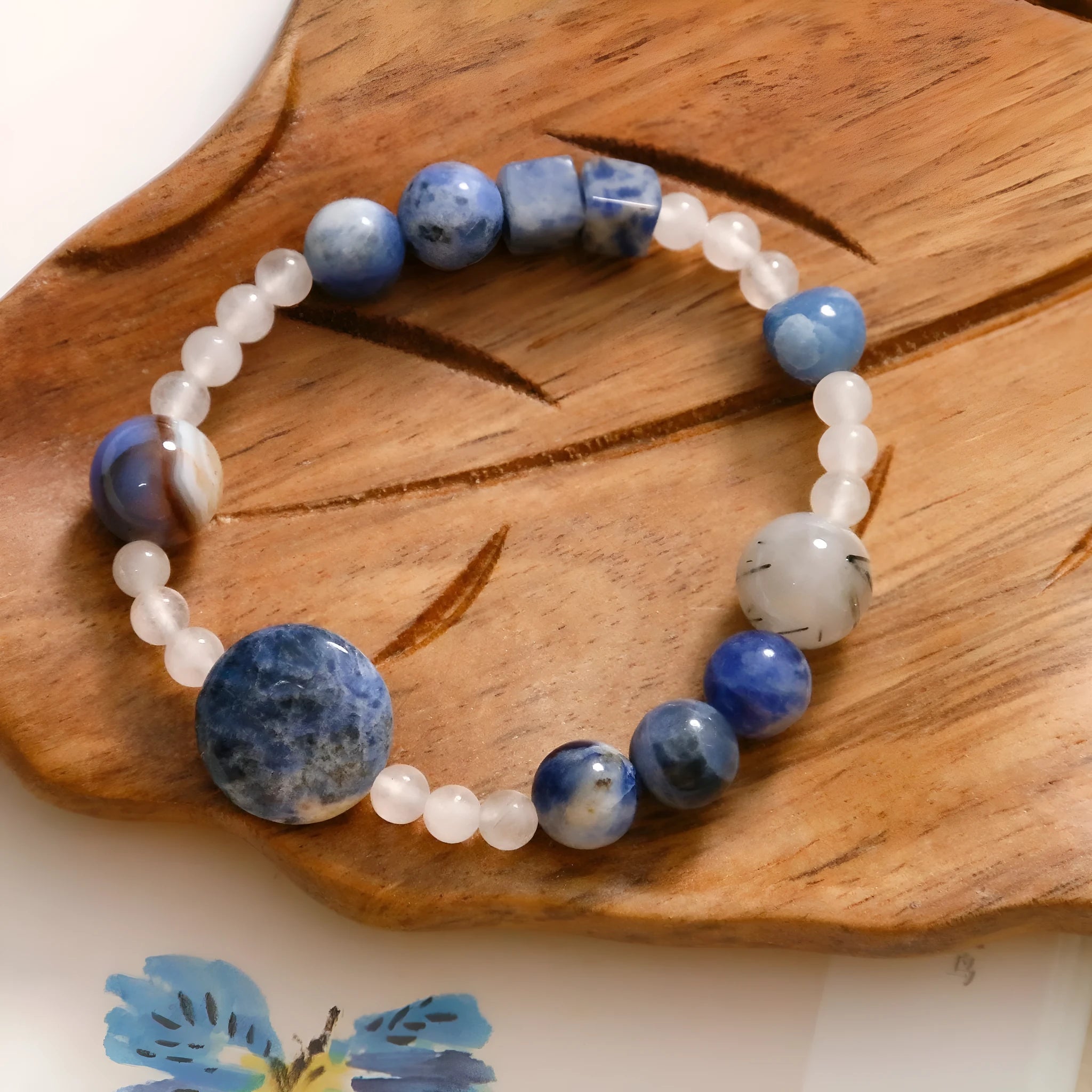 Natural blue point stone and black hair crystal agate hand-woven unisex bracelet with round and oval beads on white background