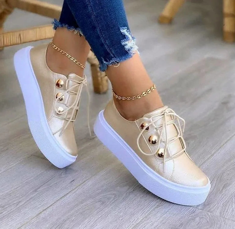 Women's white lace-up flats sneakers with silver rivet detail on a round toe.
