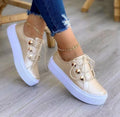 Women's white lace-up flats sneakers with silver rivet detail on a round toe.