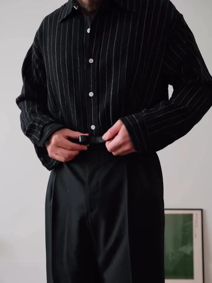 Man wearing a black pinstriped button-down long sleeve shirt with a collar.