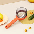 Kitchen multi-functional peeler with bucket storage in light green plastic on a clean countertop