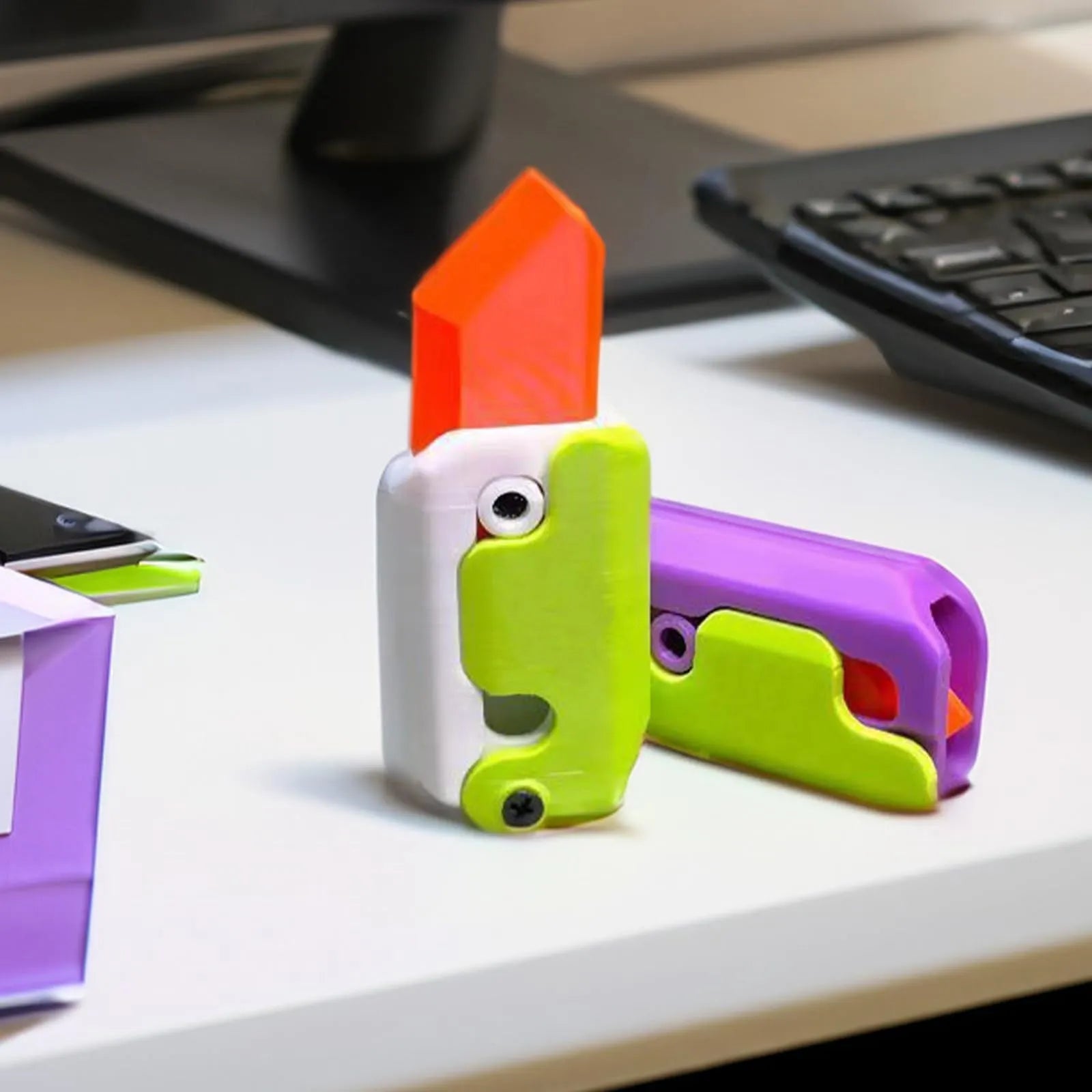 3D printed gravity carrot fidget knife in orange, purple and green colour on white background