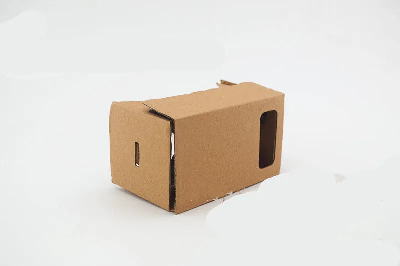 Pink and white cardboard VR headset for smartphones with adjustable straps and 3D lenses.