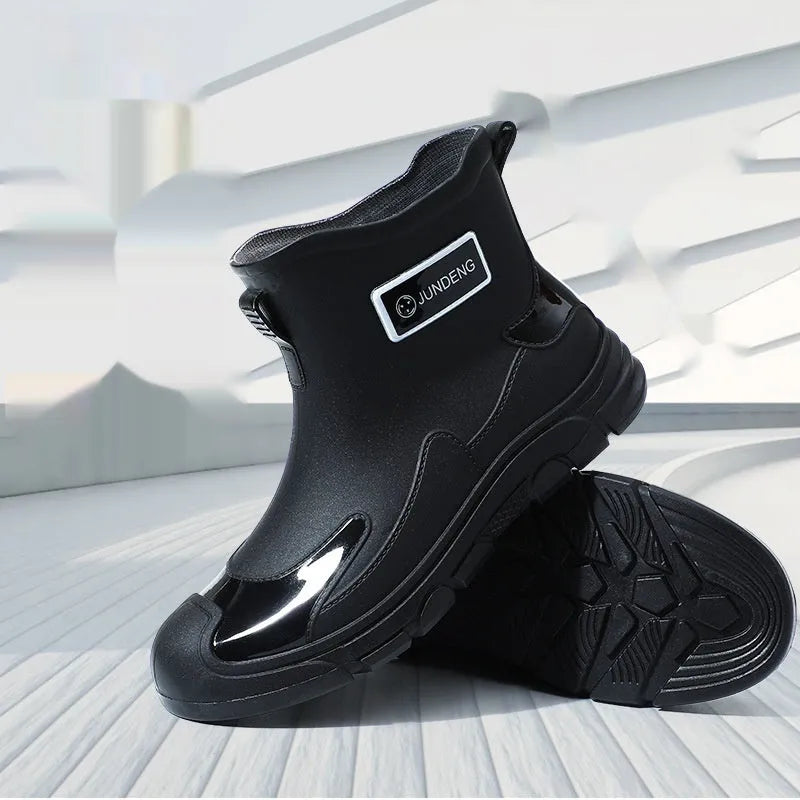 Pair of solid colour PVC rain boots with flat heel and low tube, round toe, visible sewing thread detail