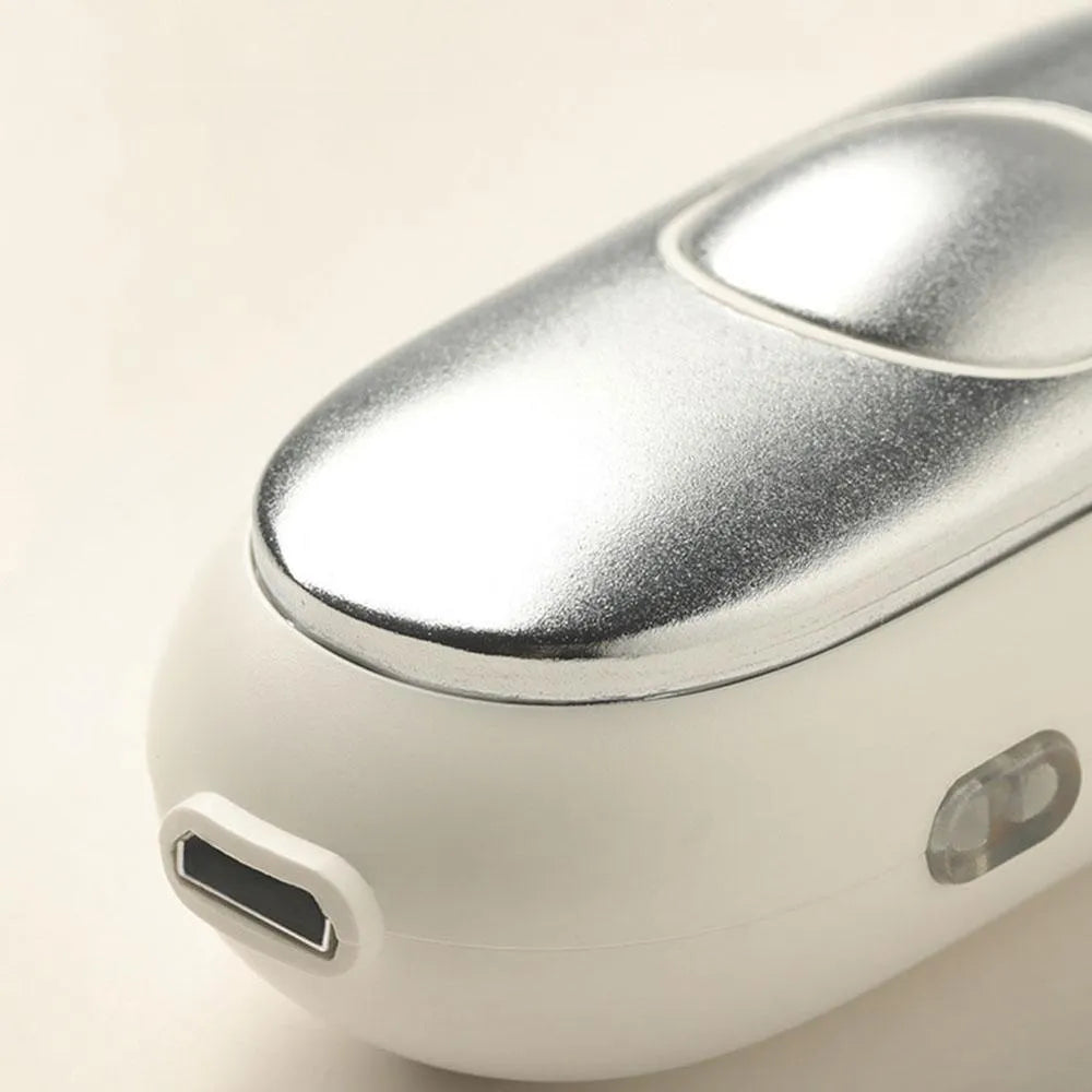 Hand-held micro-current sleep aid device in grey, with round button and micro USB port, on a desk