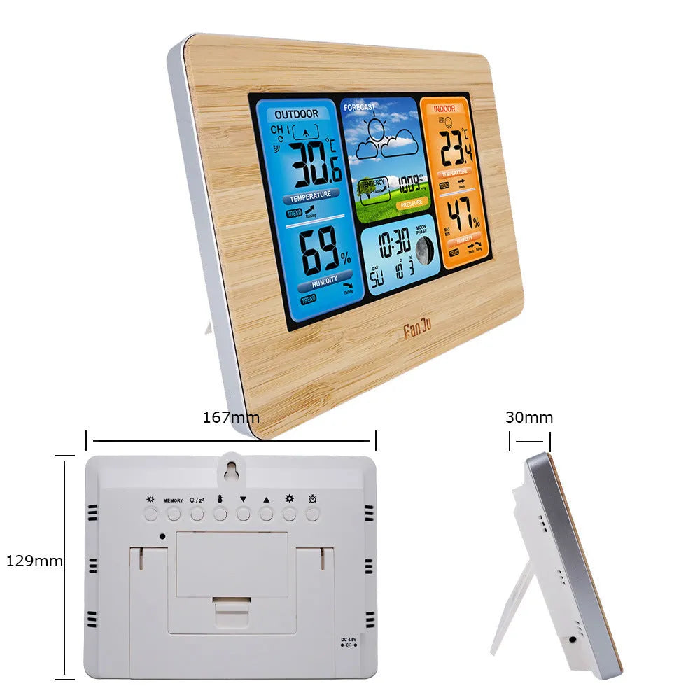 Rectangular black digital weather station with LCD display showing time, temperature, and weather icons on a desk.