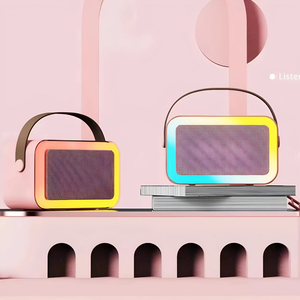 Pink portable Bluetooth karaoke speaker with microphone and coloured LED lights on a table.