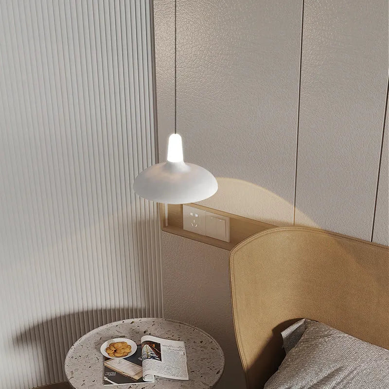 Modern minimalist adjustable bedside pendant light in Moon White shown over a small bedside table