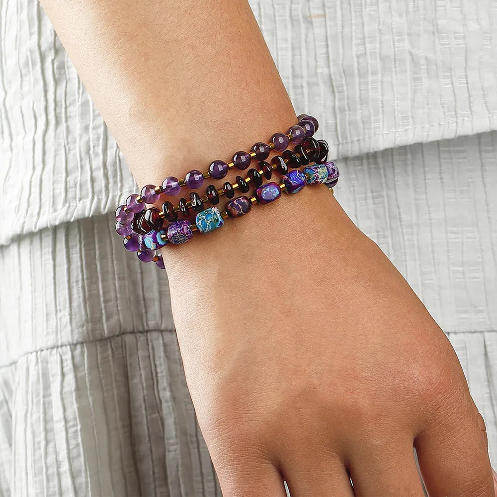Amethyst round beads stone bracelet with purple garnet and geometric texture on plain background