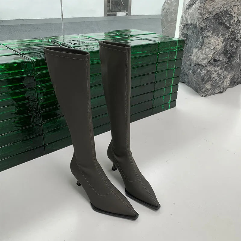 Black pointed toe women's below-the-knee stiletto boots with a back zipper on a white background