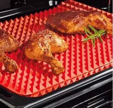 Red non-stick silicone pyramid cooking mat with grid on a baking tray for oven or BBQ use
