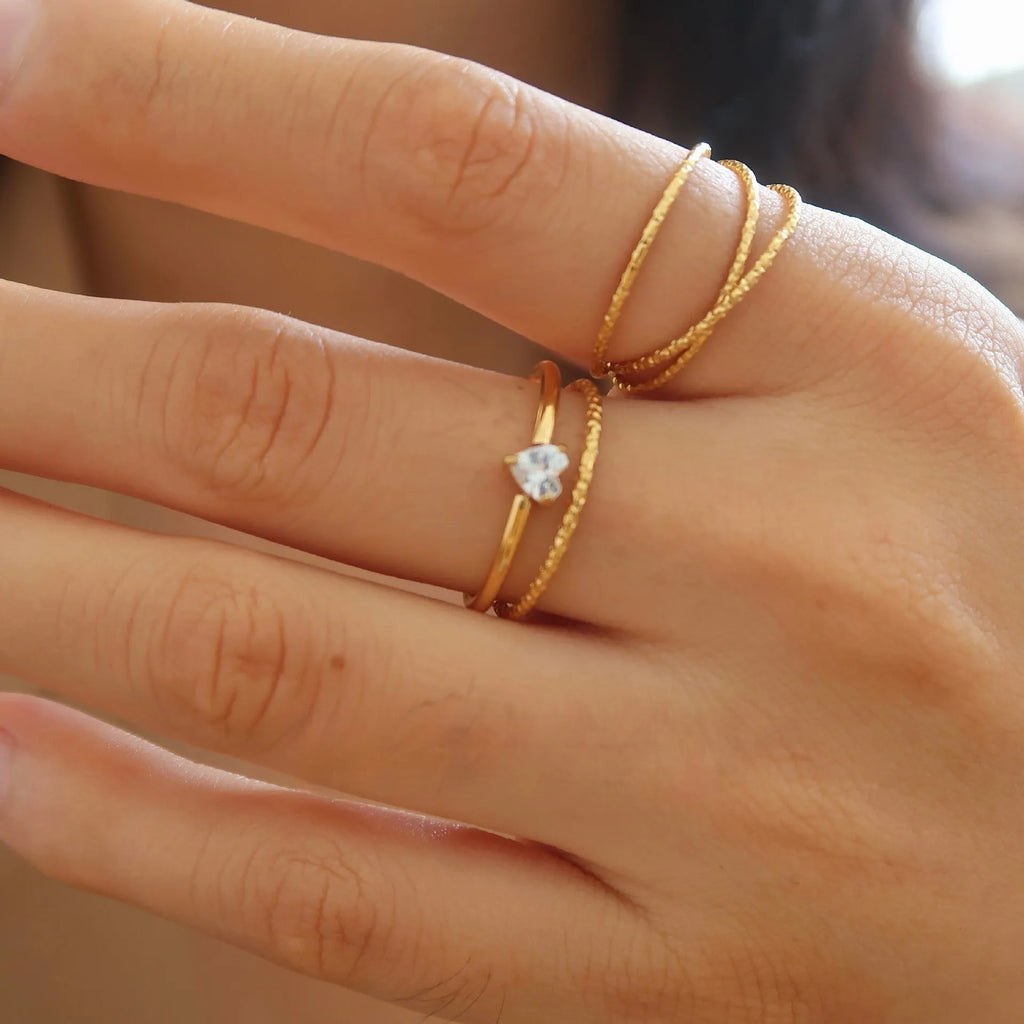 Golden stainless steel ring with heart shape on oval band, shown in size options 5 through 8