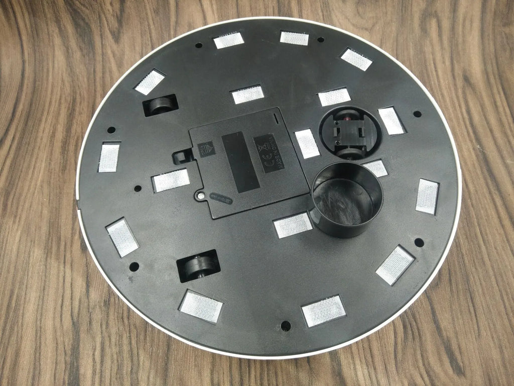 Black and white ABS robot vacuum cleaner on a wooden floor