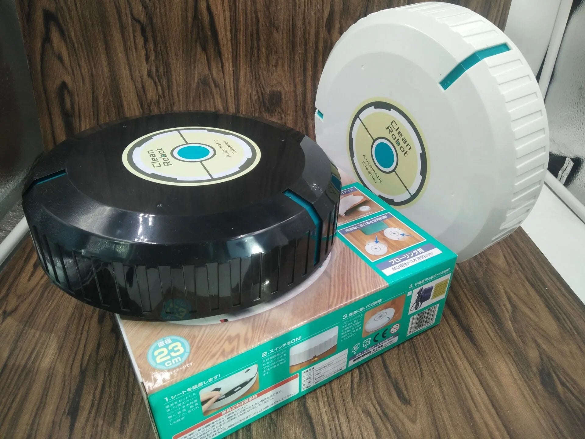 Black and white ABS robot vacuum cleaner on a wooden floor