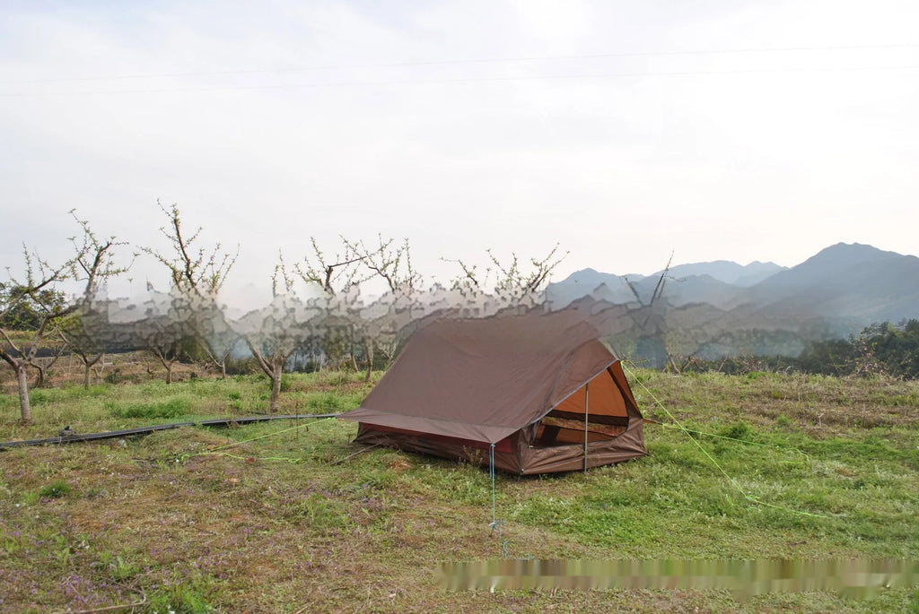 Brown A-line hiking tent set up with trekking poles in a forest clearing.