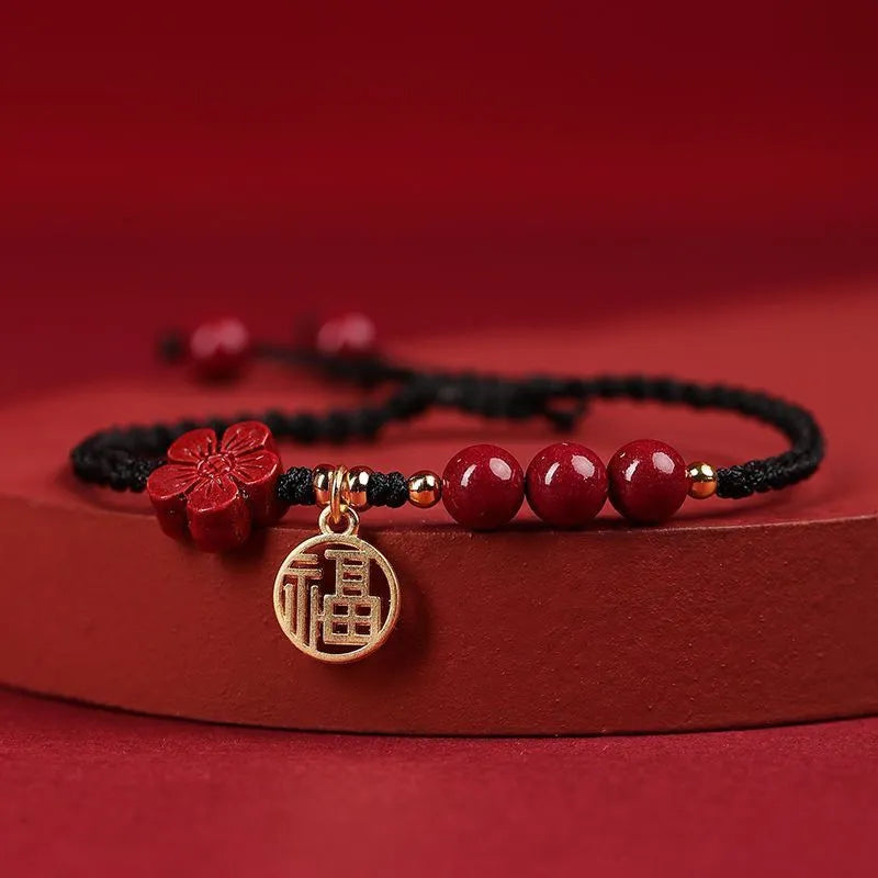Cinnabar birth year braided rope bracelet with round bead blessing card in wine red colour on a plain background.