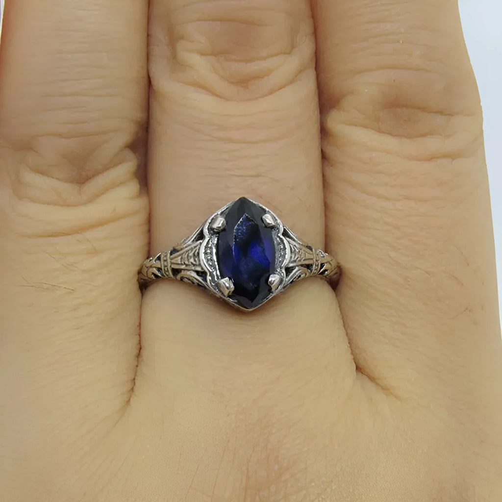 Women's silver alloy ring with geometric hollow design and central zircon stone, on a plain background