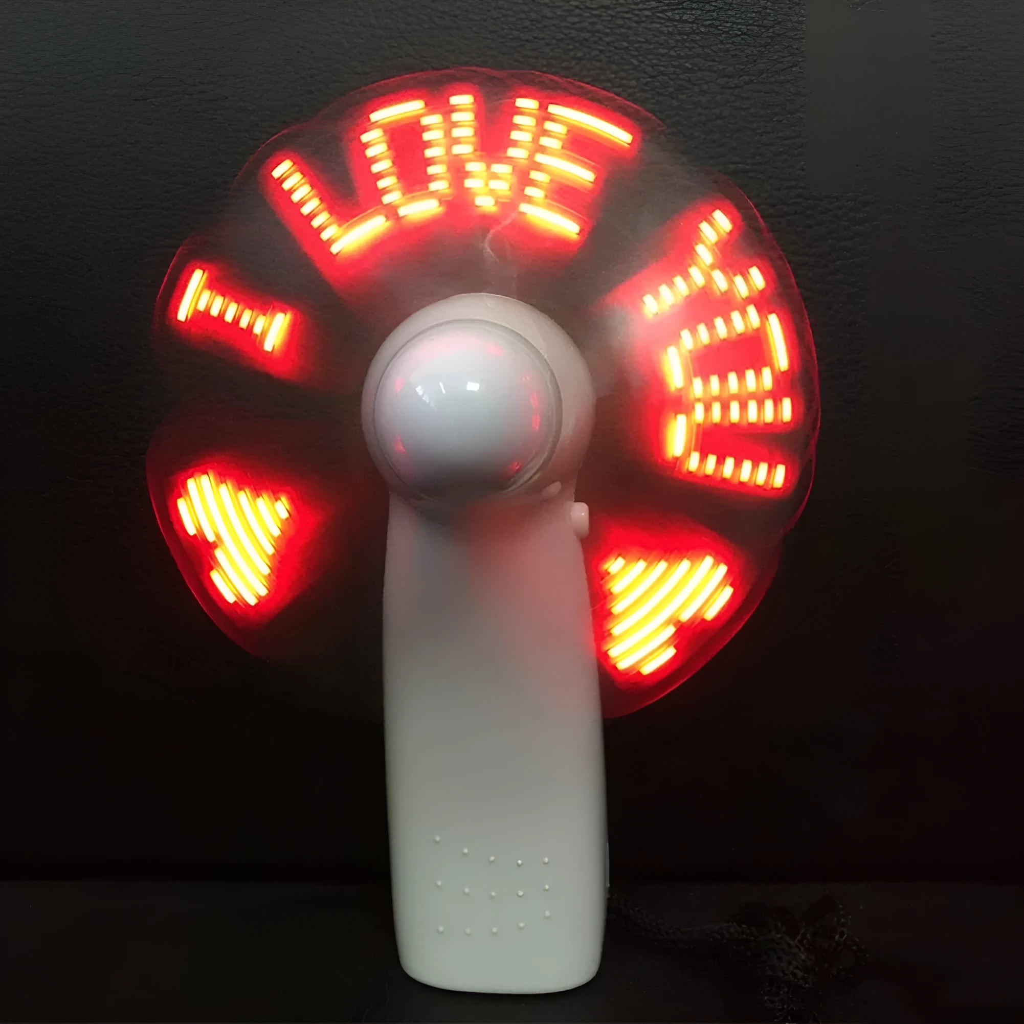 White handheld mini fan displaying blue and red LED 'I love you' pattern, shown next to a ruler for scale.