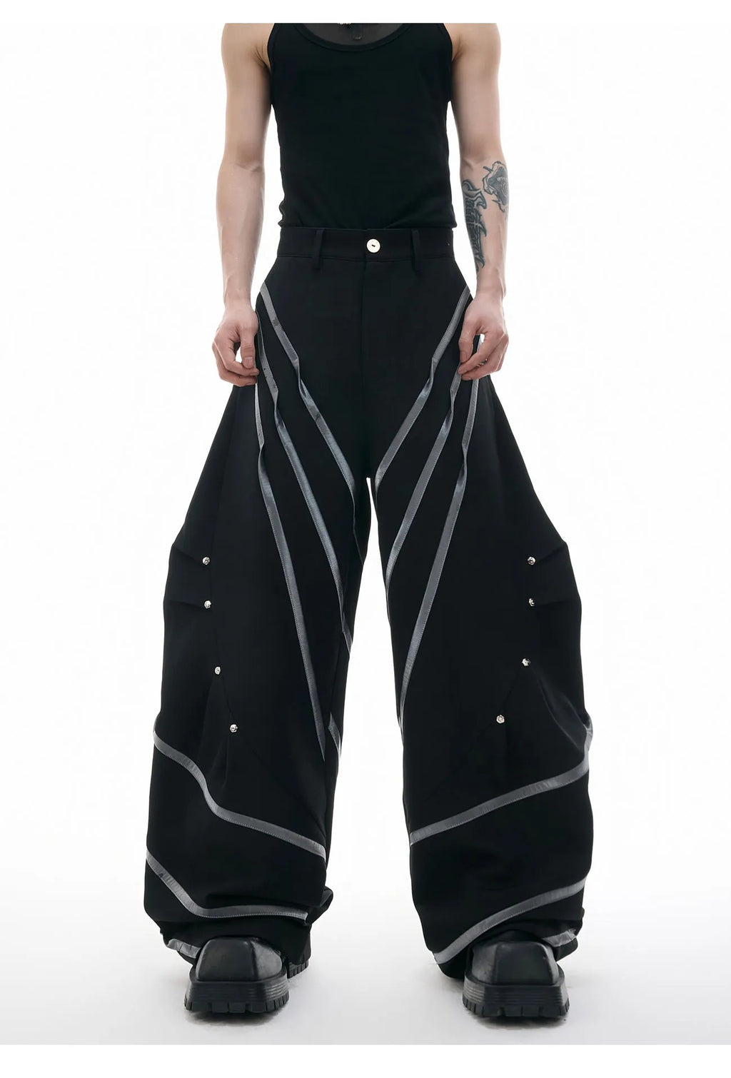 Men's black trousers with metal striped rivet details, pleated front, and a structured three-dimensional cut.