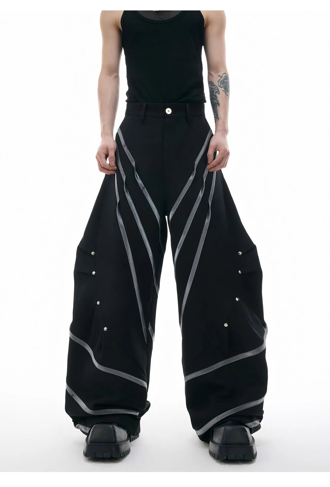Men's black trousers with metal striped rivet details, pleated front, and a structured three-dimensional cut.