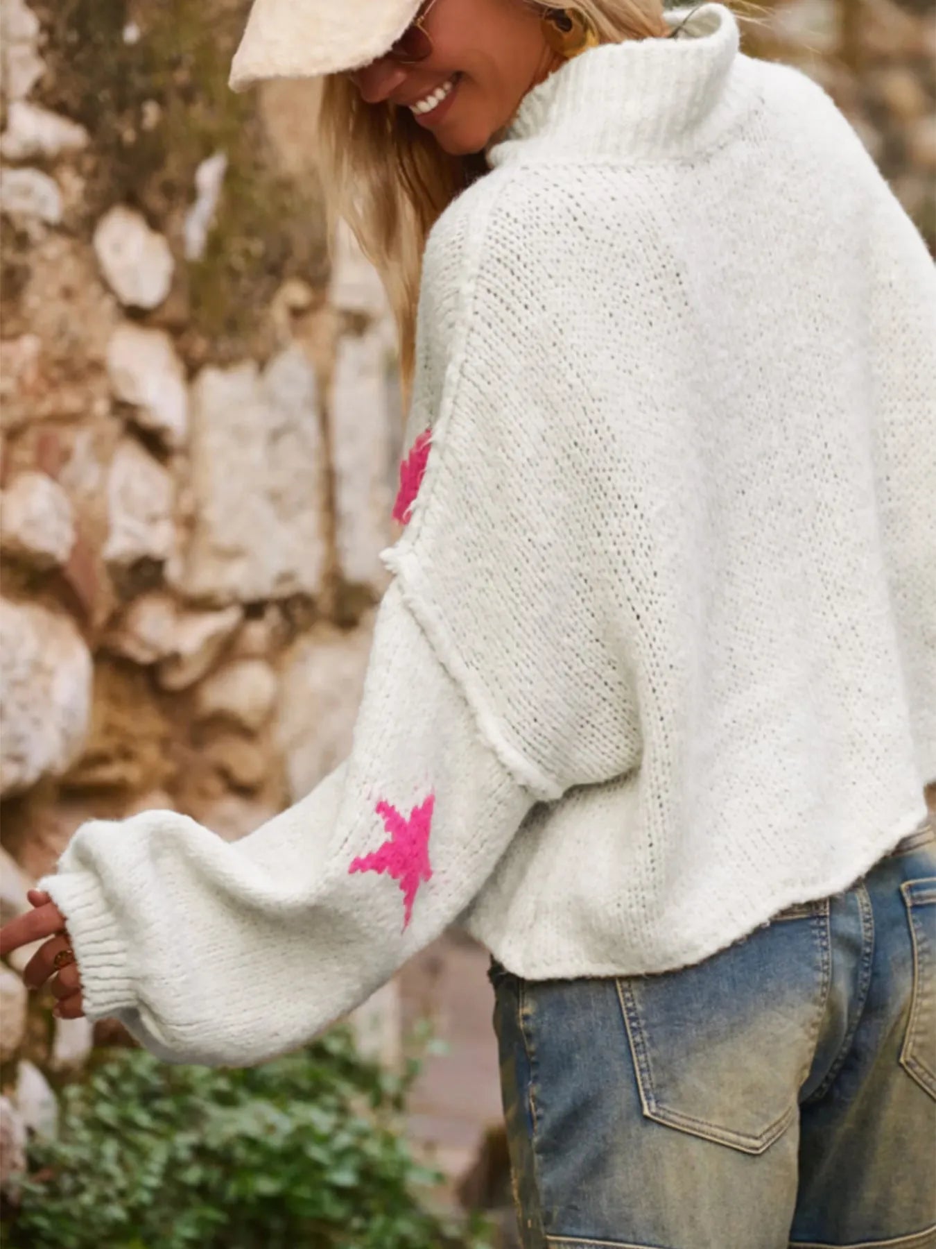 Women's white loose turtleneck pullover sweater with a black five-pointed star pattern on the front.