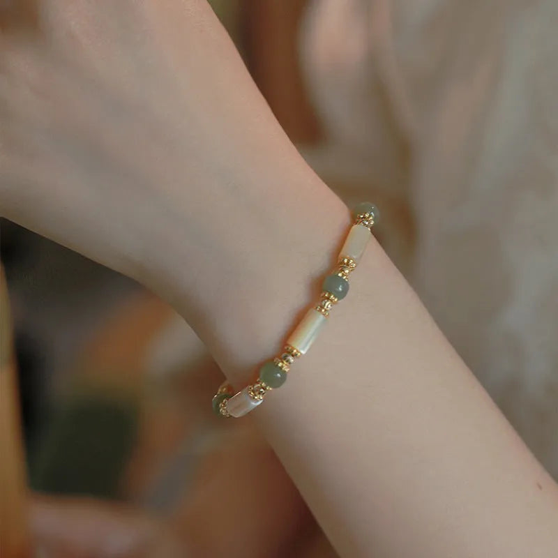 Natural Hetian jade white lip shell round bead bracelet for women on a neutral background